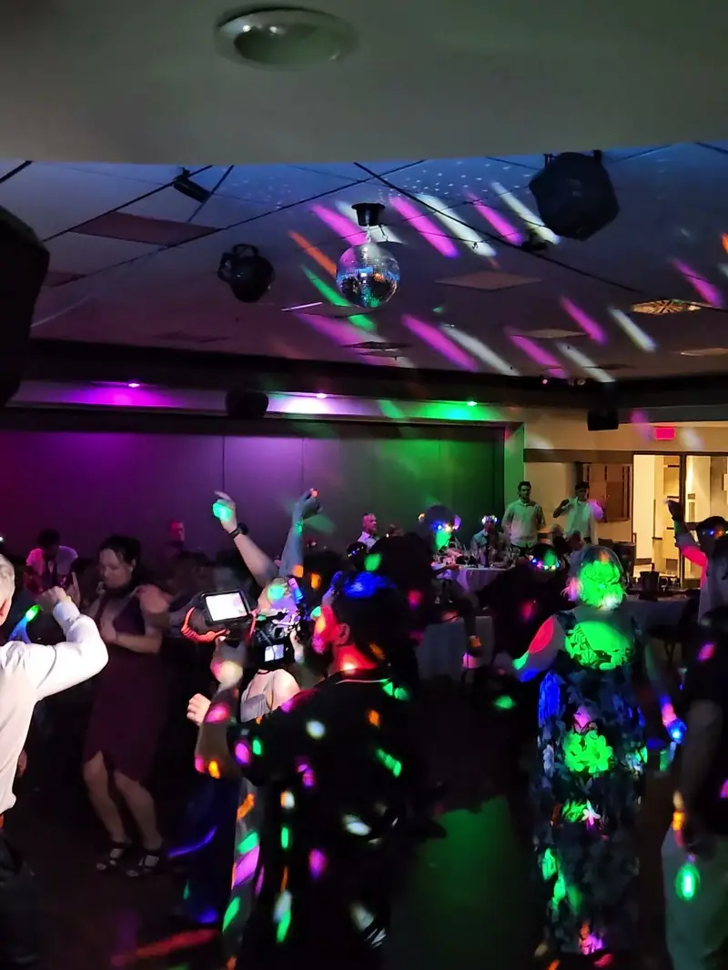 Piste de danse pleine sous une boule disco et des lumières colorées